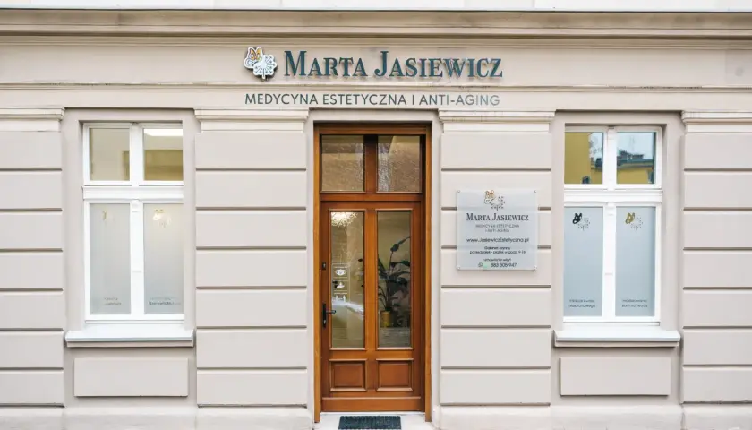 Elegancka fasada gabinetu medycyny estetycznej "Marta Jasiewicz" z drewnianymi drzwiami i oknami.