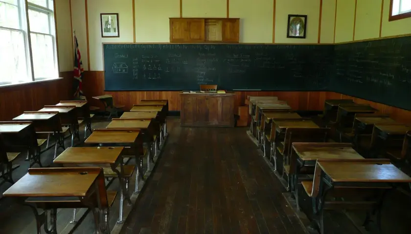 Klasa szkolna z ławkami i tablicą, gdzie widnieje statut szkoły.