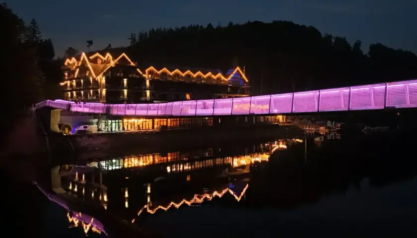 Widok na hotel z mostem oświetlonym na fioletowo, idealny na jedne z **ciekawe miejsca do 100 km od Katowic**.
