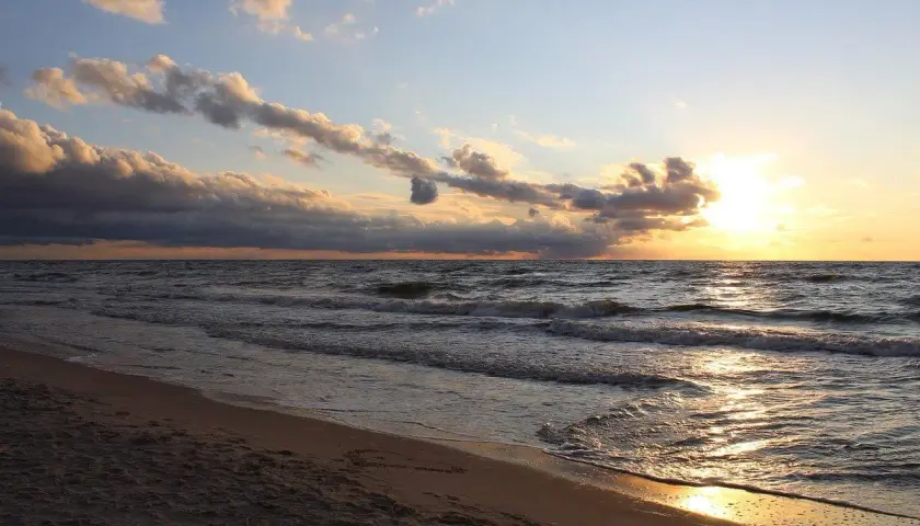Zachód słońca nad Bałtykiem, złote fale obmywają piaszczystą plażę. Idealne miejsce na kąpielisko na mierzei helskiej.
