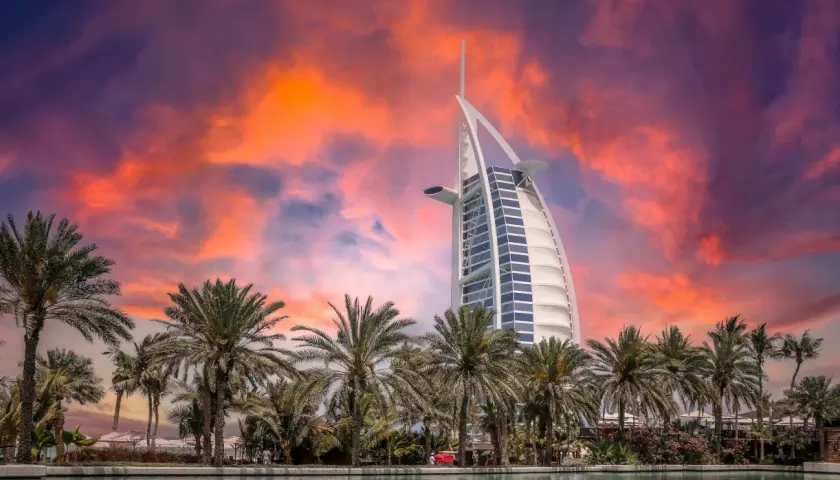 Zachód słońca nad Dubajem, palmy i hotel Burdż al-Arab. Zastanawiasz się, ile kosztuje wycieczka do Dubaju?