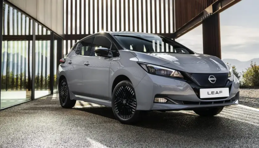 Szary Nissan Leaf stoi przed nowoczesnym budynkiem z przeszklonymi ścianami.