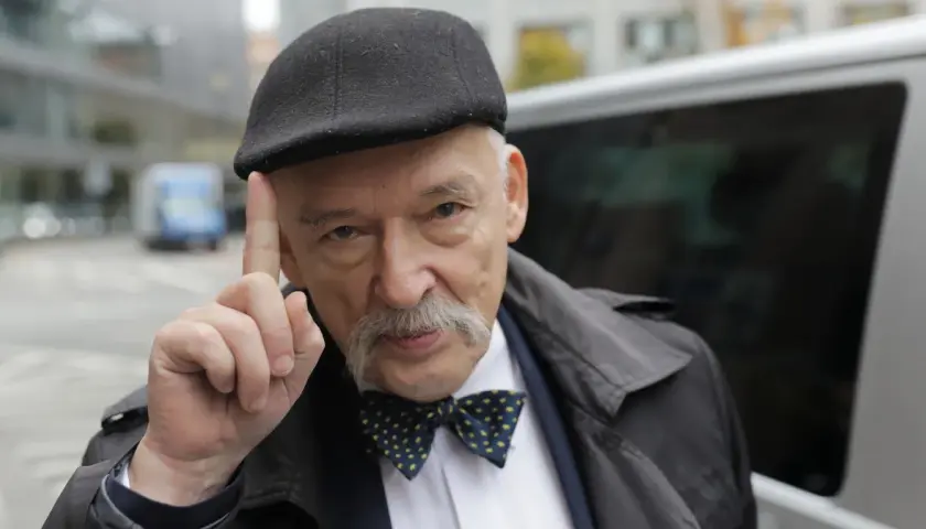 Janusz Korwin-Mikke w czapce i muszce, unoszący palec, budzi spekulacje fanów Konfederacji o jego powrocie.