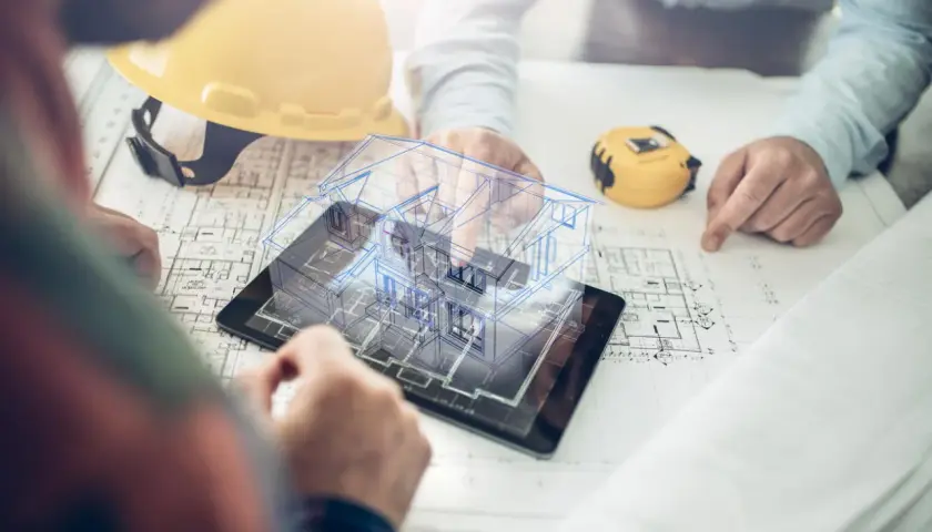 Architekci analizują projekt domu 3D na tablecie, plany i żółty kask.