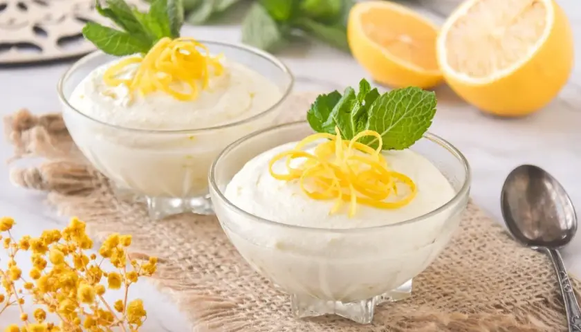 Delicioso mousse de limón con leche condensada, adornado con ralladura de limón y menta fresca.