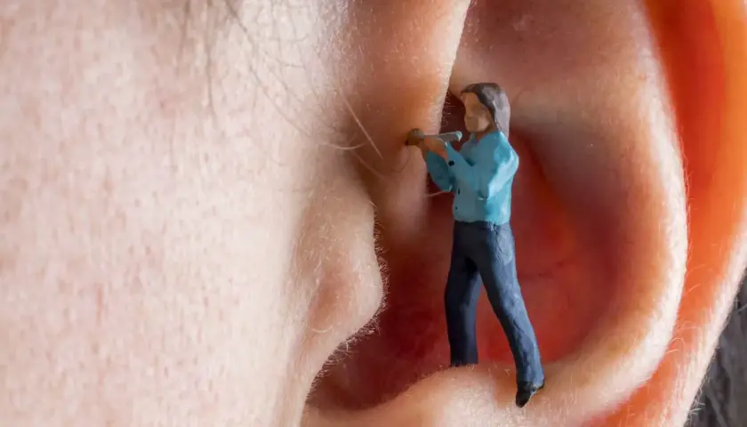 Kleine Figur im Ohr, die versucht, den Tinnitus zu bekämpfen. Vitamin B12 könnte helfen.