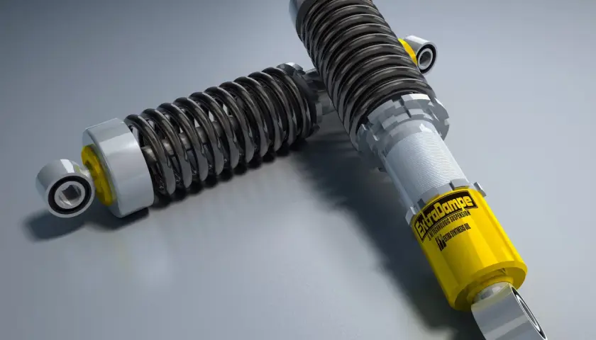 Dos amortiguadores de coche, uno amarillo con la marca "ExtraDampe", esenciales para entender qué son los amortiguadores de un coche.