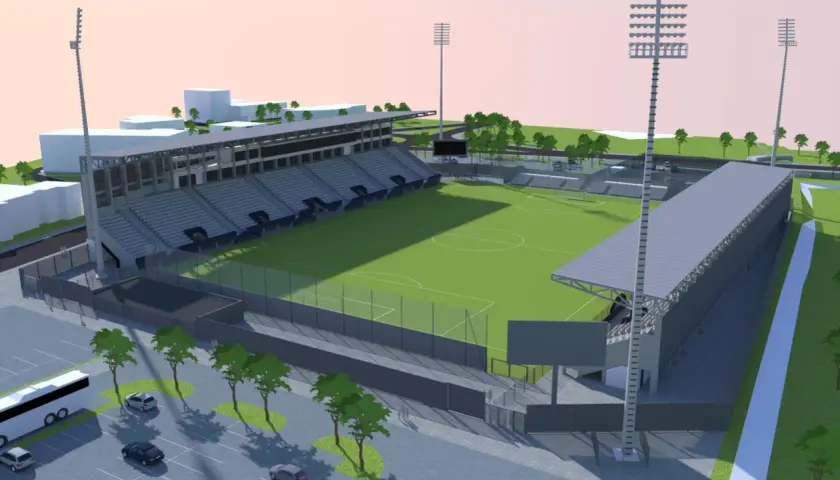 Nowoczesny stadion Sandecji z zieloną murawą, trybunami i oświetleniem.