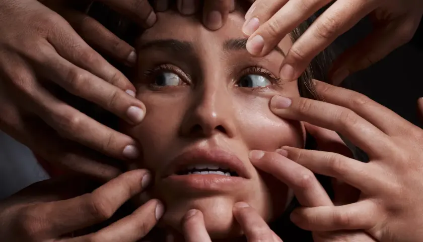 Volto di donna circondato da mani che la stringono, espressione di disagio, forse un simbolo del disturbo schizoide di personalità.