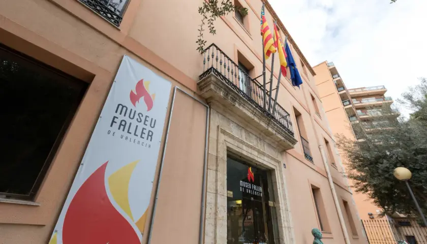Fachada del Museu Faller de València con un cartel anunciador y banderas ondeando.
