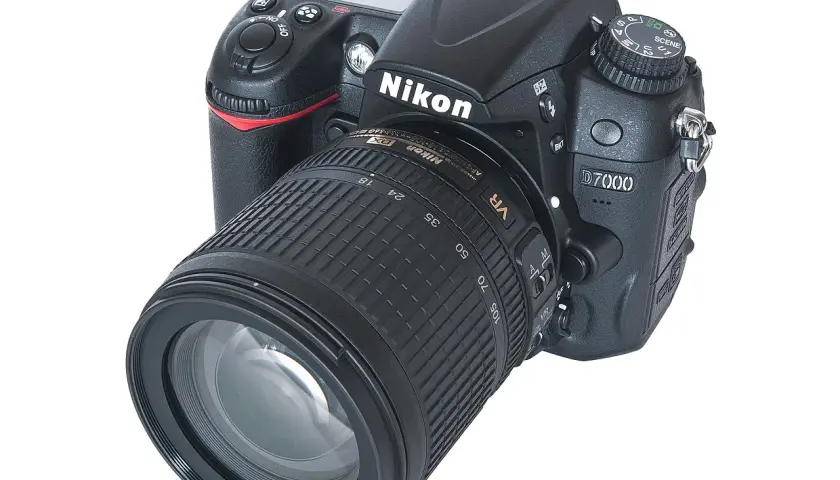 Nikon D7000 z obiektywem 18-105mm VR. Aparat cyfrowy z widocznymi przyciskami i pokrętłem trybów. Dane techniczne tego modelu są imponujące.