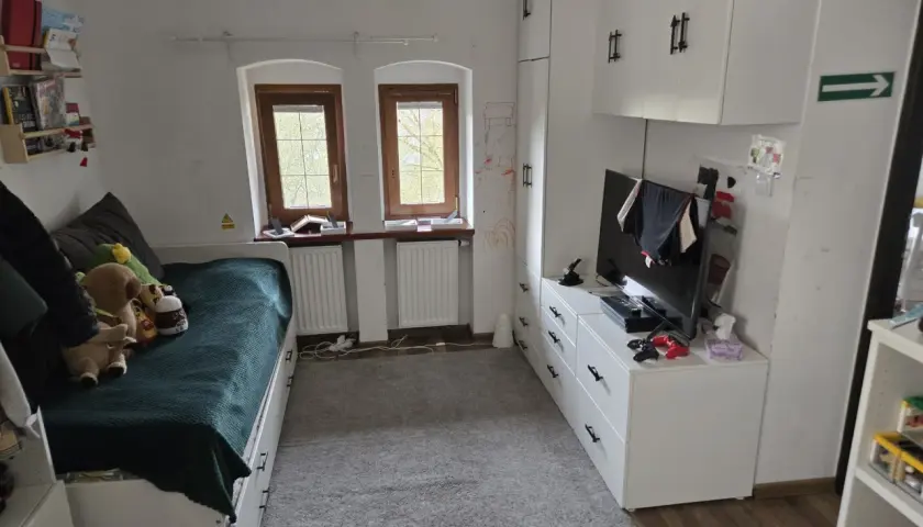 Pokój z łóżkiem, szafami i telewizorem. Idealne miejsce, by zamienię mieszkanie własnościowe na mniejsze.
