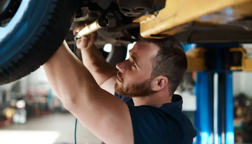 Mechanik sprawdza podwozie auta. Dowiedz się, ile kosztuje badanie techniczne samochodu osobowego.