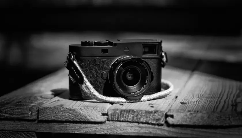 Klasyczny aparat Leica M10 Monochrom z obiektywem na drewnianym blacie.