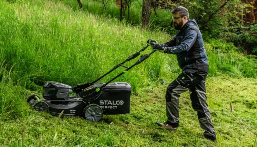 Mężczyzna z kosiarką elektryczną STALCO PERFECT. Zastanawiasz się, jaką kosiarkę traktorek kupić? Forum podpowie!