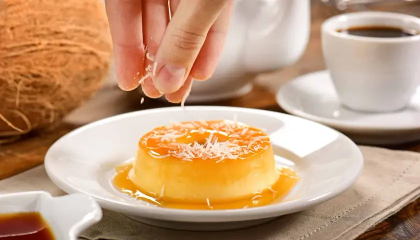Un flan au lait de coco sans four, garni de noix de coco râpée, prêt à être dégusté avec un café.