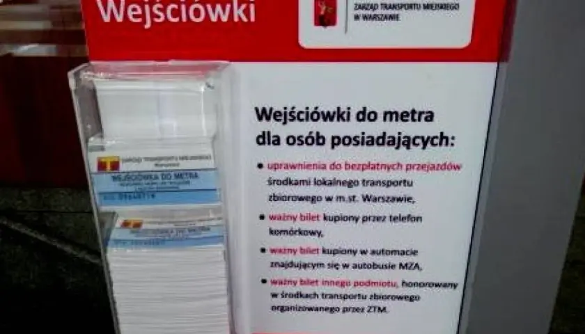 Informacja o tym, jak kupić bilet na metro w Warszawie. Stojak z ulotkami "Wejściówki do metra" i informacją o uprawnieniach.