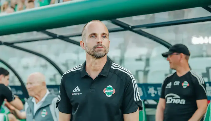 Trener Radomiaka w czarnej koszulce z herbem klubu, skupiony na boisku.