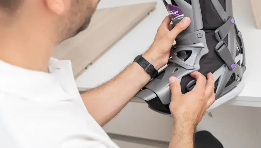 Mann mit weißem Poloshirt passt eine orthopädische Schiene an, die auf einem Rezept für orthopädische Schuhe basiert.
