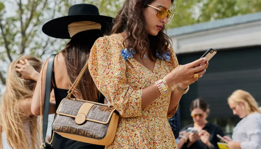 Kobieta w kwiecistej sukience i okularach przeciwsłonecznych, z torebką Fendi, uosabia styl boho moda.