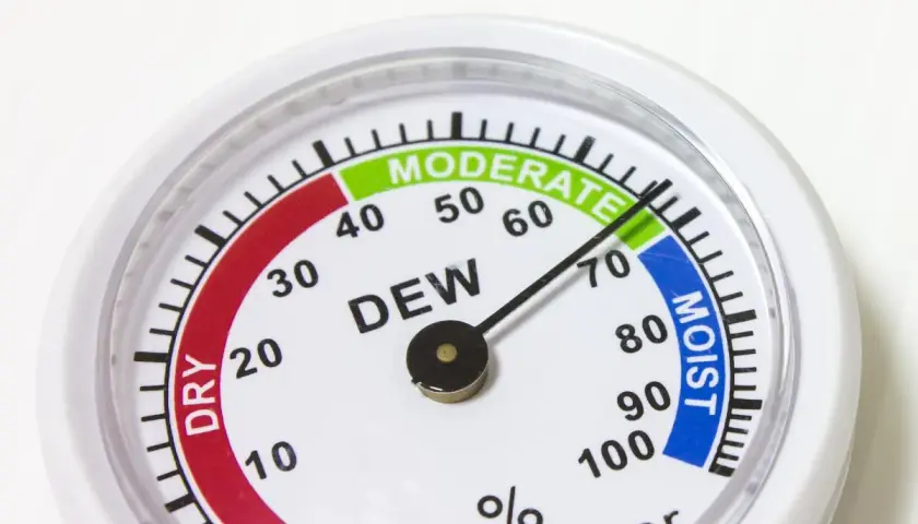 Un higrómetro que mide la humedad del aire, con zonas indicadas como "DRY", "MODERATE" y "MOIST".