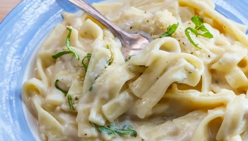Pyszny makaron z tuńczykiem w sosie śmietanowo-serowym, udekorowany świeżą bazylią i parmezanem. Idealny na szybki obiad.