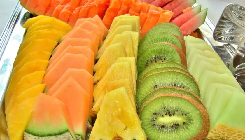 Présentation de fruits pour mariage : plateau coloré de pastèque, melon, papaye, ananas et kiwi coupés en éventail.