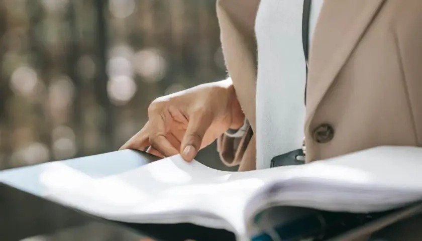 Dłoń przegląda dokumenty, przygotowując uruchomienie kredytu hipotecznego.