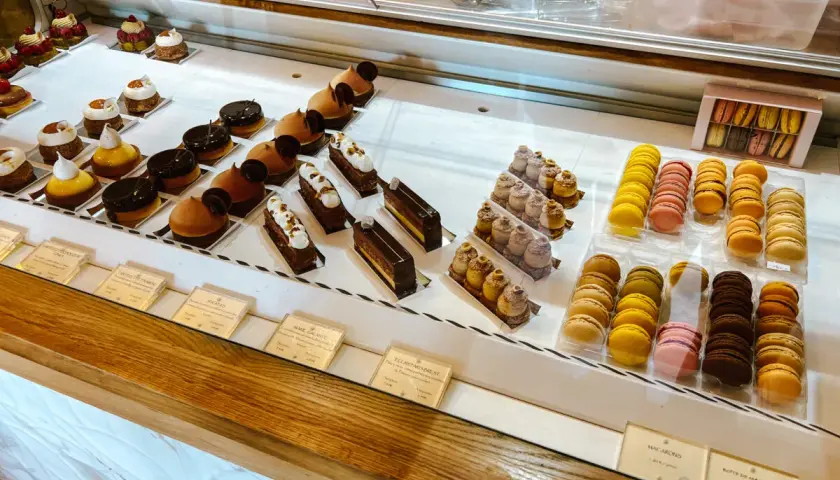 Witryna cukierni z wykwintnymi deserami, w tym makaronikami i ciastkami, idealna dla szukających najlepszych francuskich restauracji.