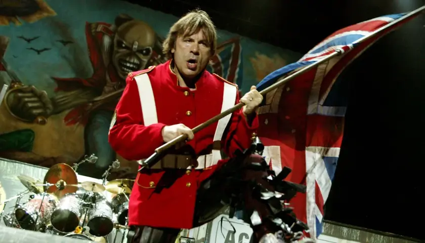 Bruce Dickinson z zespołu Iron Maiden na scenie z flagą Wielkiej Brytanii i Eddie'm w tle.