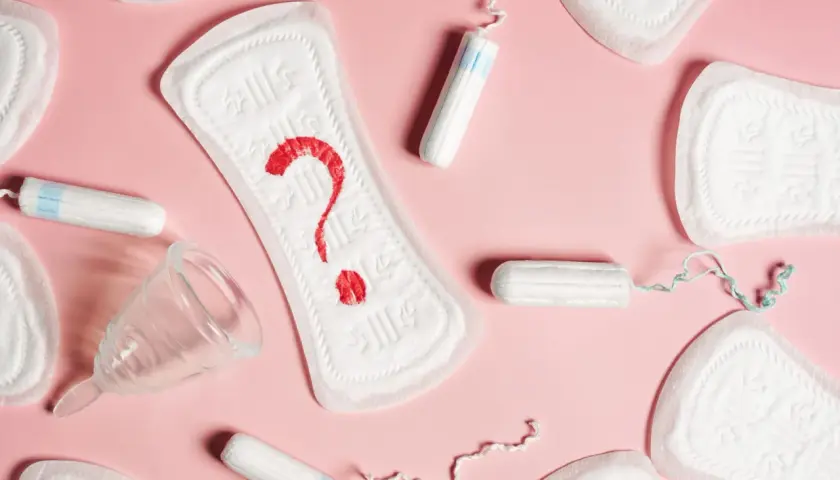 Plamienie 3 dni po okresie? Podpaski, tampony i kubeczek menstruacyjny na różowym tle.