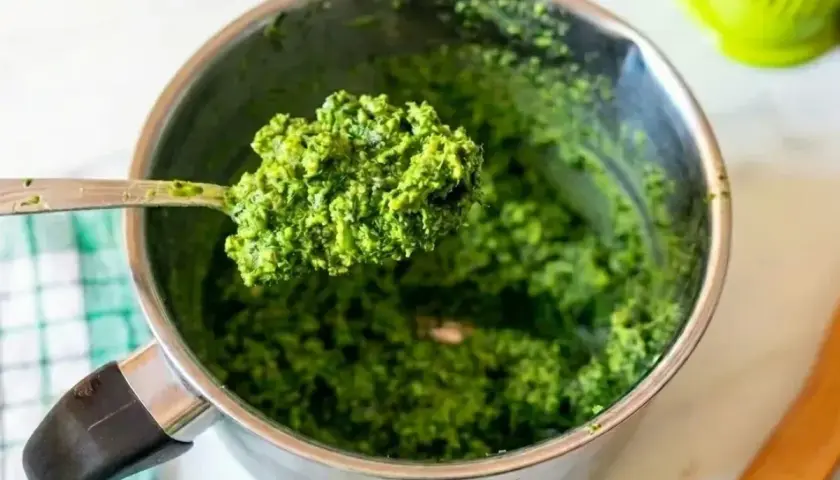 Łyżka świeżego, zielonego pesto bazyliowego nad metalowym garnkiem. Idealne do makaronu!