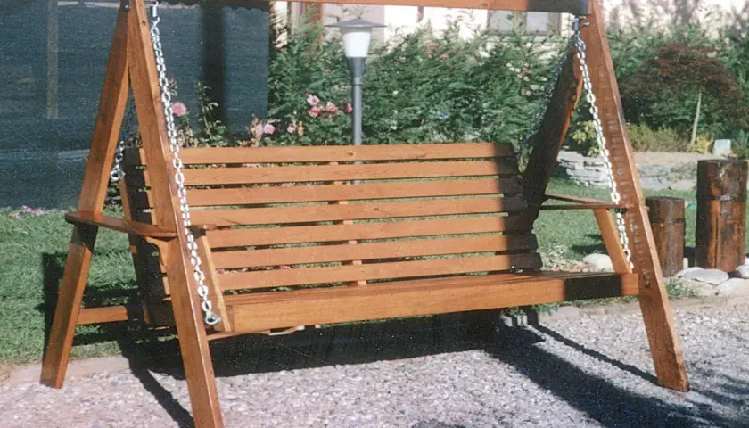 Un dondolo in legno fai da te, con seduta a doghe, è pronto per rilassarsi in giardino.