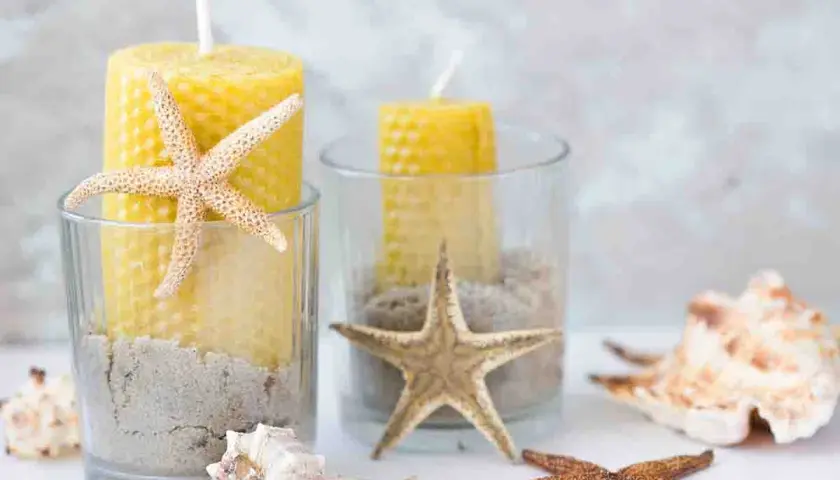 Candelabri fai da te con candele gialle, sabbia e stelle marine in bicchieri di vetro. Un tocco marino per la tua casa.