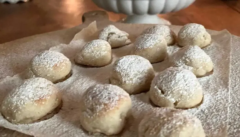 Små, pudrade bakverk som påminner om torta caprese, ligger utspridda på bakplåtspapper.