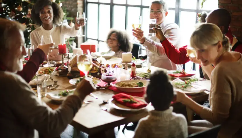 Familie feiert Weihnachten am festlich gedeckten Tisch. Alle stoßen an, die Stimmung ist fröhlich. Das ist die beste Weihnachtsrede!