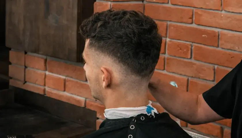 Mężczyzna z modną fryzurą fade, której nadano objętość za pomocą prestyler do włosów.