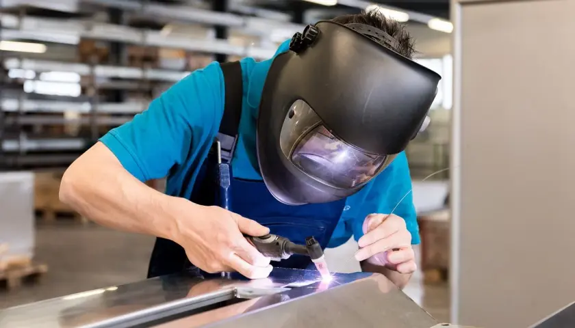 Uczeń na kursie spawacza TIG precyzyjnie łączy metalowe elementy, skupiony na pracy.