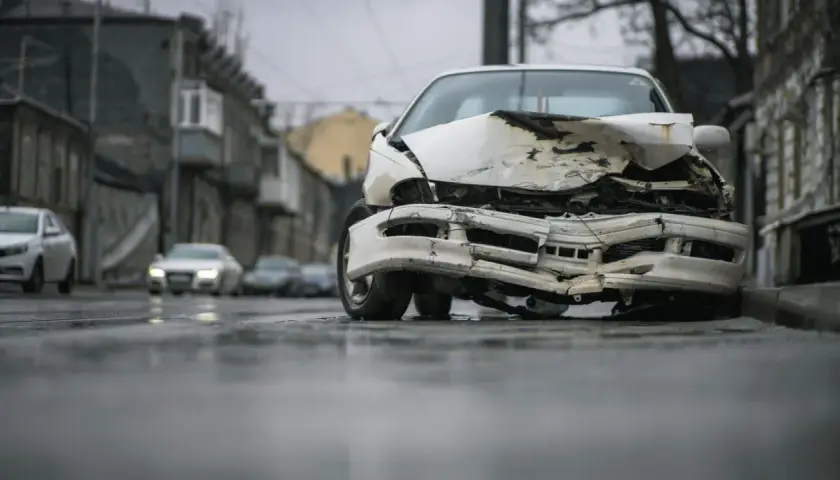 Zniszczony biały samochód na ulicy. Po wypadku, czas pomyśleć, jak wyrejestrować samochód.