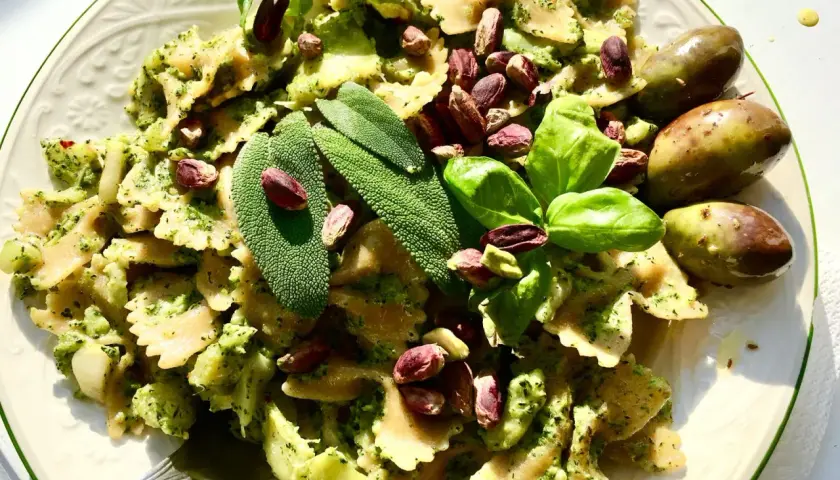 Farfalle condite con un saporito pesto di salvia, pistacchi e basilico fresco, guarnite con olive verdi.