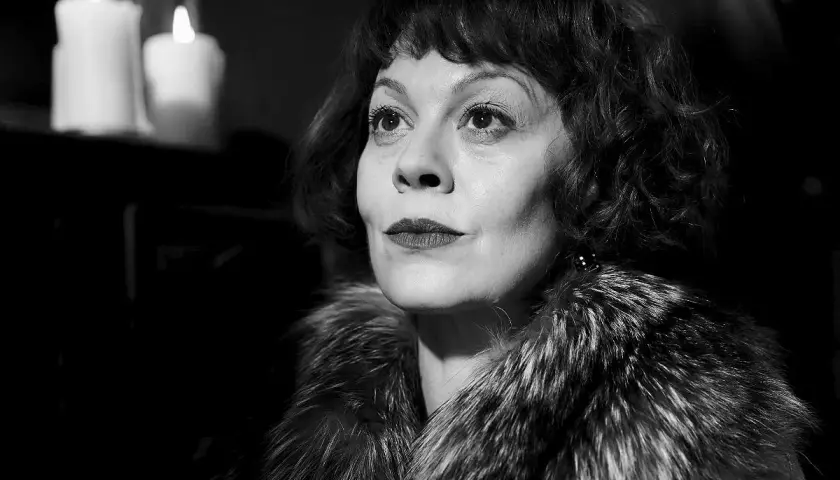 Helen McCrory, znana z roli Narcyzy Malfoy w Harry Potter, w eleganckim futrze i przy świecach.