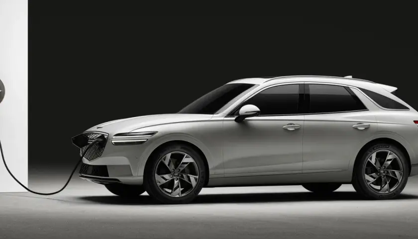 Biały Genesis GV70 na ładowarce. Elegancki SUV z charakterystycznym grillem i światłami LED.