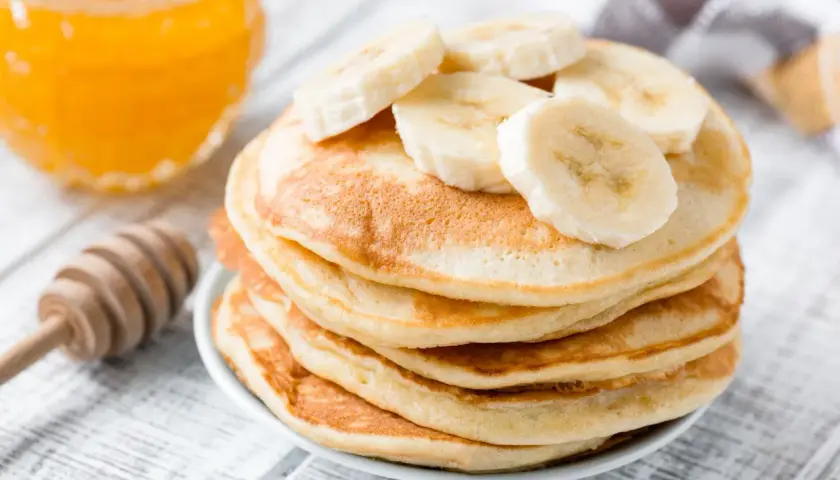 Pancake perfetti, dorati e soffici, preparati con la friggitrice ad aria, guarniti con fette di banana e miele.