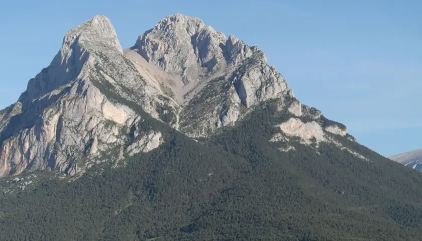 Majestuoso Pedraforca, cumbre rocosa coronada por pinos. Una ruta de senderismo desafiante espera.