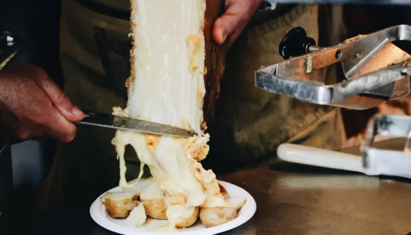 Un morceau de fromage à raclette classique fond sur des pommes de terre. Le fromage dégouline, prêt à être servi.