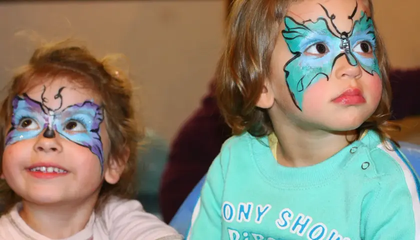 Bambine con colorate maschere di carnevale facili a forma di farfalla dipinte sul viso, pronte per la festa.