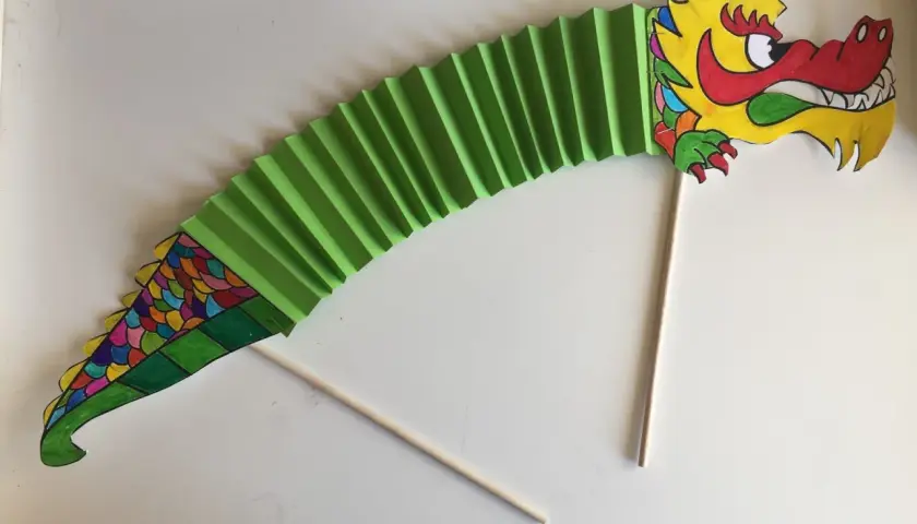 Dragón de papel verde, parte de un manualidades proyecto china infantil. Cabeza colorida y cuerpo en acordeón.
