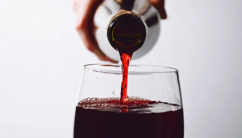 Rotwein wird in ein Glas gegossen. Die Frage, ob man Rotwein nach 2 Wochen noch trinken kann, beschäftigt viele Genießer.