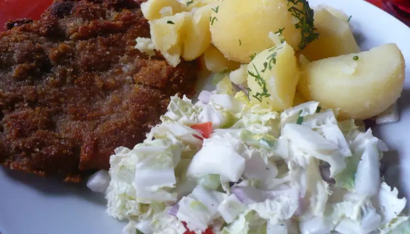 Kotlet schabowy z ziemniakami i surówką z białej kapusty.