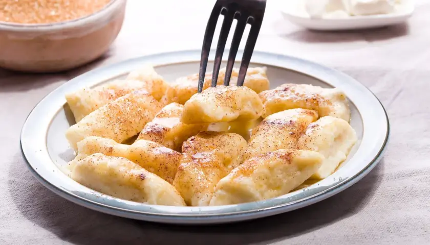 Pyszne pierogi leniwe posypane cynamonem, gotowe do jedzenia. Idealne na szybkie śniadanie lub deser.